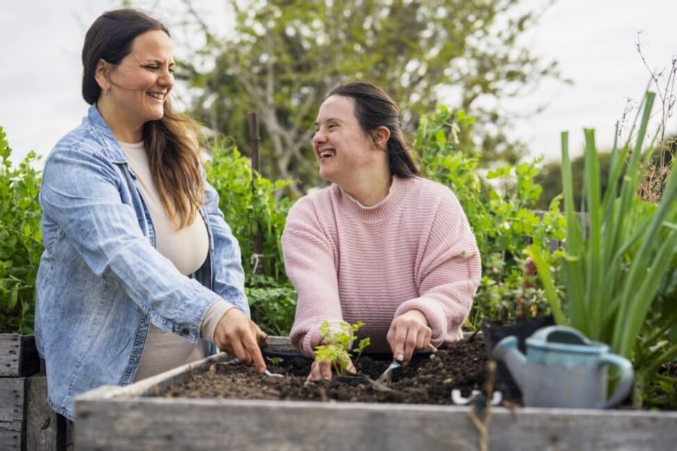 Mother and daughter with down syndrome having fun while working on garden